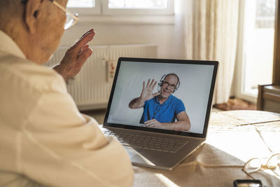 Midsection of man using mobile phone while sitting on table