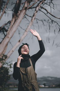 Full length of woman standing by tree against sky