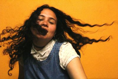 Young woman with tousled hair against orange background