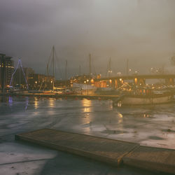 Sailboats moored in river against sky at night