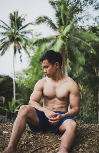 Shirtless muscular man sitting on land