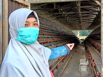 Portrait of young woman standing in chicken coop