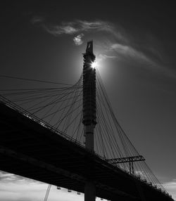 Low angle view of suspension bridge against cloudy sky