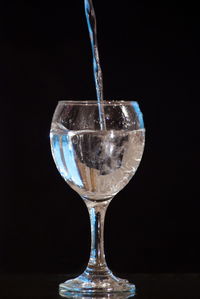 Close-up of wineglass on glass against black background