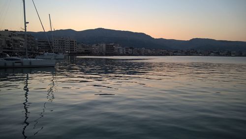 Sailboats moored in harbor at sunset