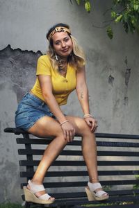 Portrait of smiling young woman sitting against wall