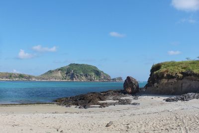 Rocks on beach against blue sky