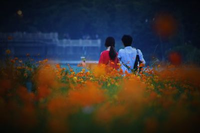 Rear view of couple with orange flowers blooming outdoors