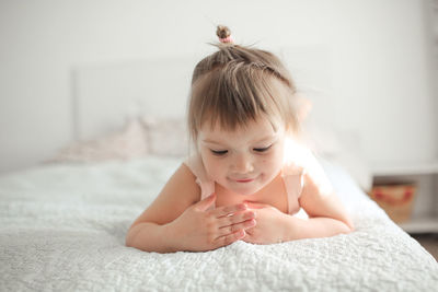 Funny girl toddler with a smile lying on the bed, close-up, concept happy happy childhood, 