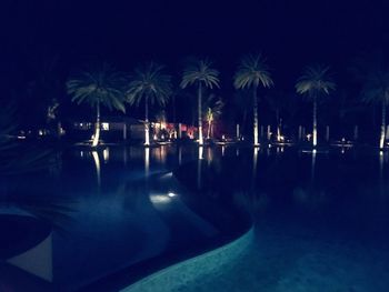 Swimming pool by sea against sky at night