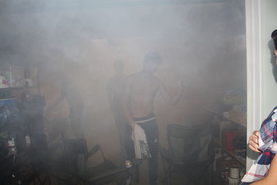 Shirtless man standing in smoky room