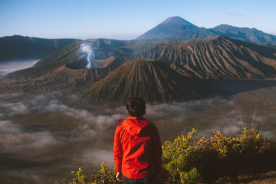 Rear view of boy looking at mountains against sky