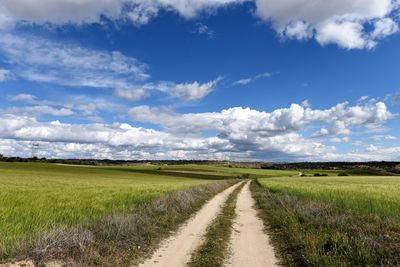 Road amidst field against sky