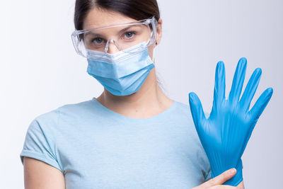 Portrait of doctor in mask wearing surgical glove against gray background