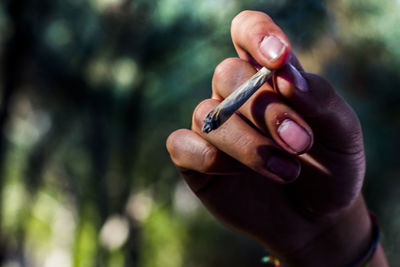 Midsection of person holding cigarette