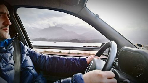 Midsection of man sitting in car against sky