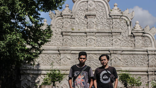 Portrait of male friends standing against historic temple