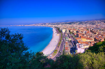 High angle view of buildings and sea against blue sky