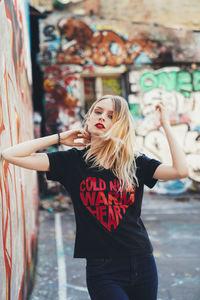 Full length of woman standing against graffiti wall