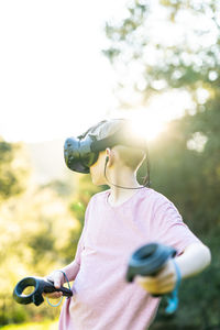 Teen having virtual experience with vr headset and controllers outside