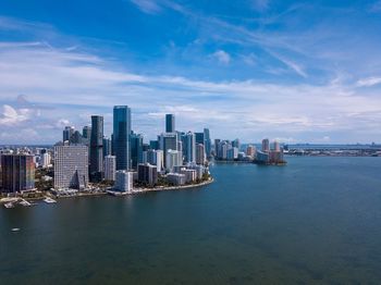 Sea and modern buildings in city against sky