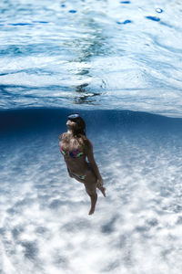 Young woman swimming in a beach with crystal clear water in canary islands