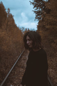 Portrait of young woman standing on railroad track