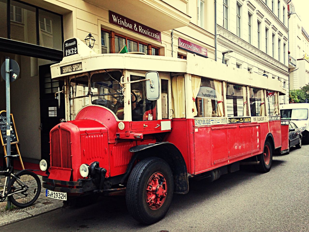 transportation, mode of transport, land vehicle, red, architecture, building exterior, car, built structure, bicycle, stationary, parking, parked, travel, city, street, day, vintage car, bus, outdoors, incidental people