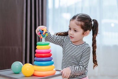 Girl playing with multi colored toys at home