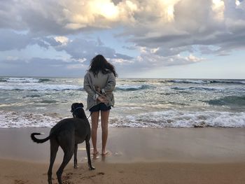 Full length of girl with dog on beach against sky