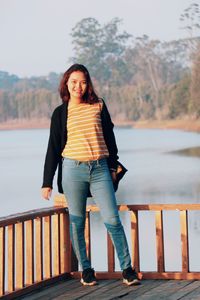 Portrait of smiling woman standing against railing