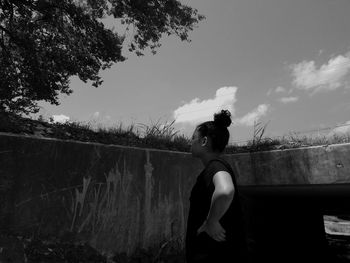 Woman standing by tree against sky