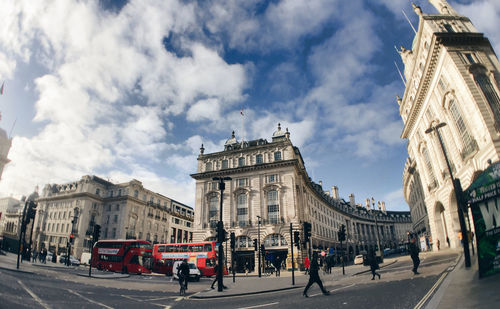 People walking on street by buildings against sky