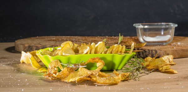 Some deep-fried spiral-sliced potatoes with some thyme on wooden board