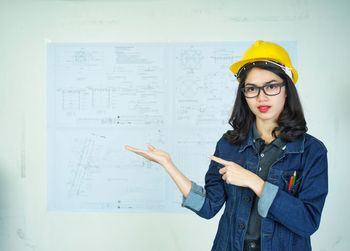 Young woman standing against yellow wall