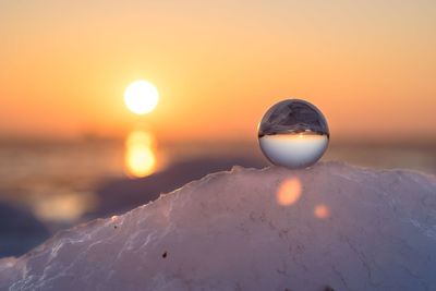 Close-up of snow on sea against sky during sunset