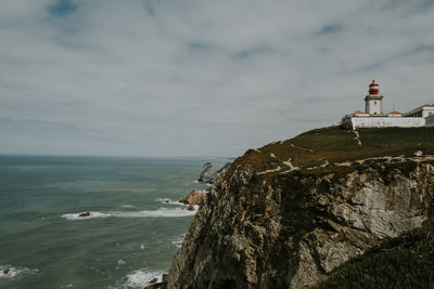 Lighthouse by sea against sky