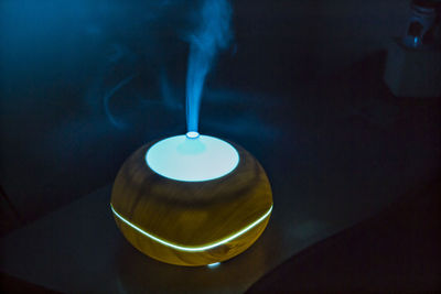 Close-up of illuminated electric lamp with smoke on table