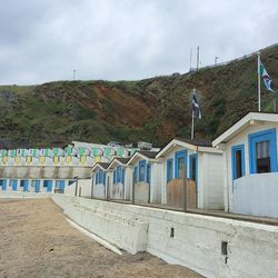 Beach huts on shore against mountains