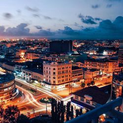 Illuminated cityscape against sky during sunset