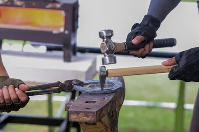 Close-up of men hammering metal at workshop