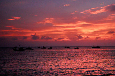 Silhouette boat sailing on sea against sky at sunset