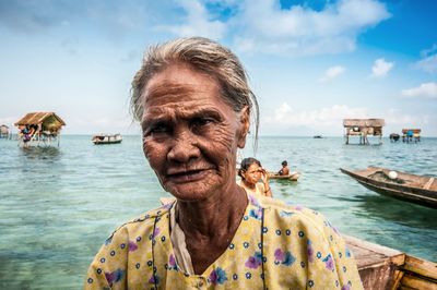 Portrait of senior woman at beach against cloudy sky