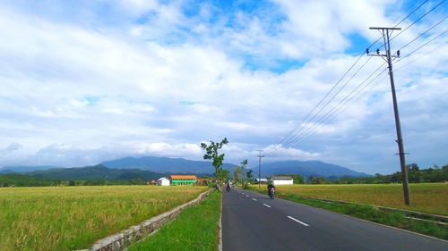 Road by field against sky