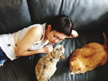 High angle view of woman with cats lying on sofa at home