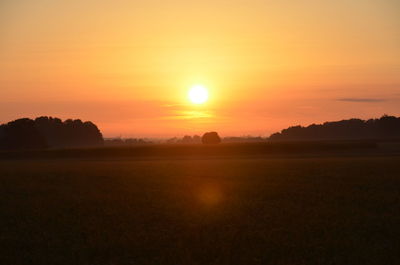 Scenic view of silhouette field against orange sky