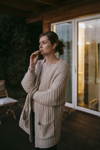 Thoughtful woman brushing teeth while standing on porch