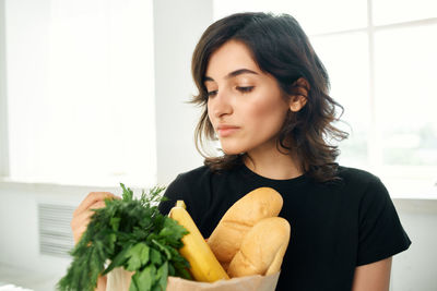 Young woman looking away while standing at home