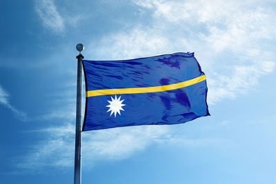 Low angle view of flag against blue sky