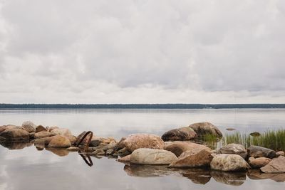 Rocks by lake against sky